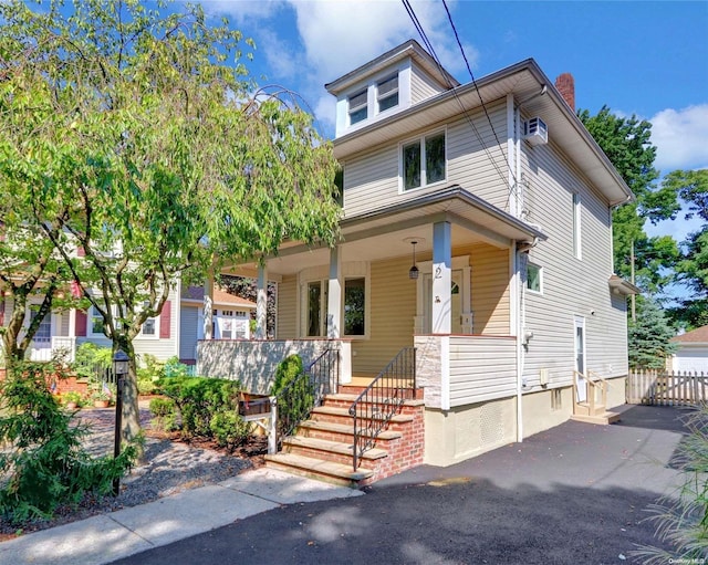 view of front facade with covered porch and a wall unit AC