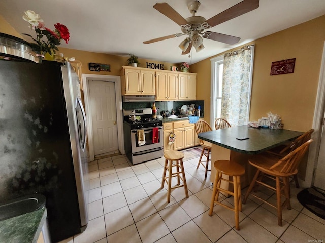 kitchen with backsplash, a kitchen breakfast bar, ceiling fan, light tile patterned floors, and stainless steel appliances