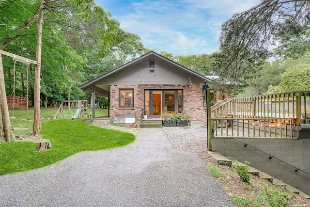 bungalow featuring a playground, a deck, and a front lawn