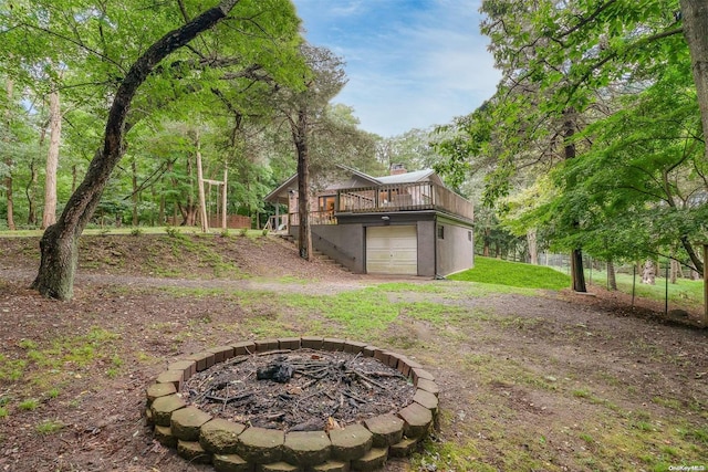 view of yard with a fire pit, a garage, and a deck