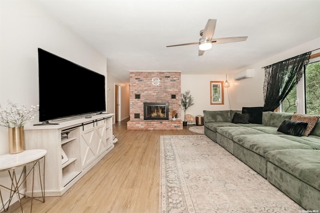 living room with a wall mounted air conditioner, light hardwood / wood-style flooring, a fireplace, and ceiling fan