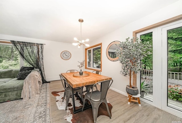 dining area featuring baseboard heating, light hardwood / wood-style flooring, and an inviting chandelier