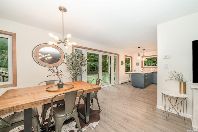 dining area with light hardwood / wood-style flooring, an inviting chandelier, and baseboard heating