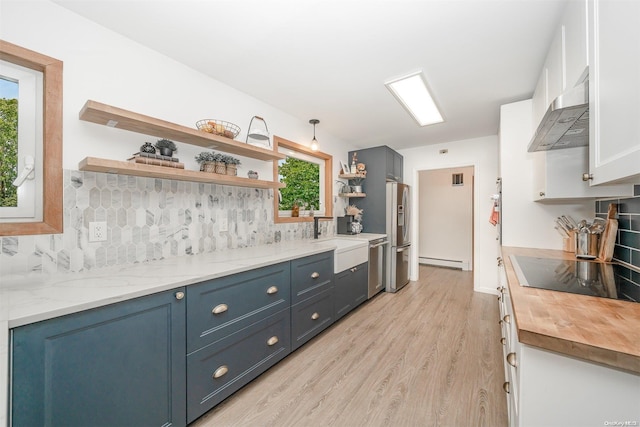 kitchen featuring butcher block counters, white cabinetry, a baseboard radiator, light wood-type flooring, and wall chimney exhaust hood