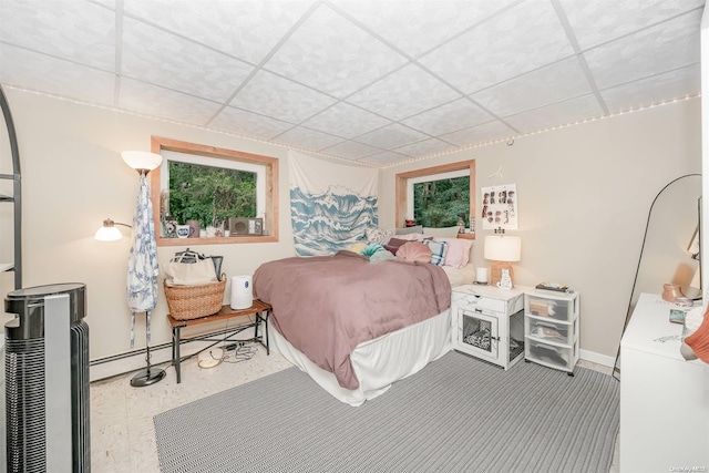 bedroom featuring a baseboard heating unit and a drop ceiling