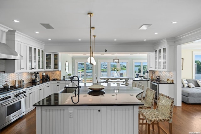 kitchen featuring a kitchen bar, white cabinetry, a center island with sink, and double oven range