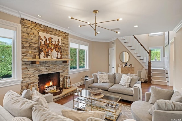 living room featuring hardwood / wood-style flooring, a stone fireplace, a healthy amount of sunlight, and crown molding