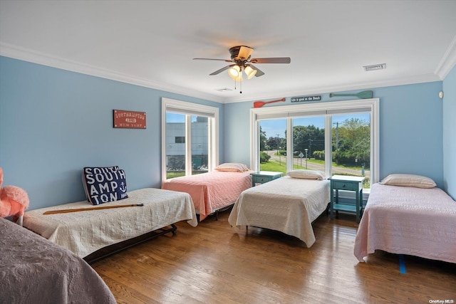 bedroom featuring ceiling fan, wood-type flooring, crown molding, and multiple windows