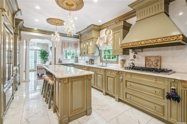 kitchen featuring stainless steel gas stovetop, a center island, premium range hood, and decorative columns