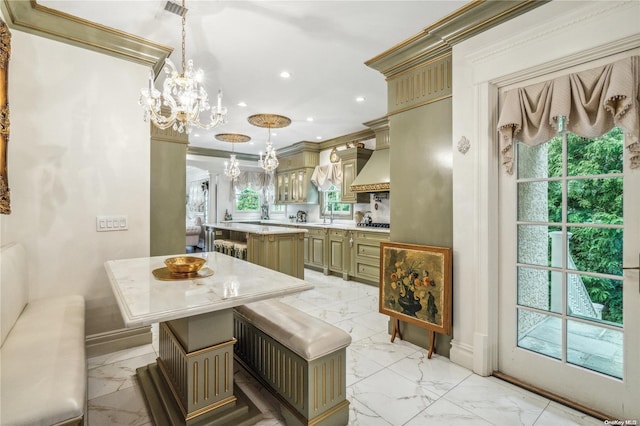 kitchen featuring pendant lighting, sink, ornamental molding, a kitchen island, and a chandelier