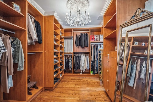 spacious closet featuring light hardwood / wood-style floors and a notable chandelier