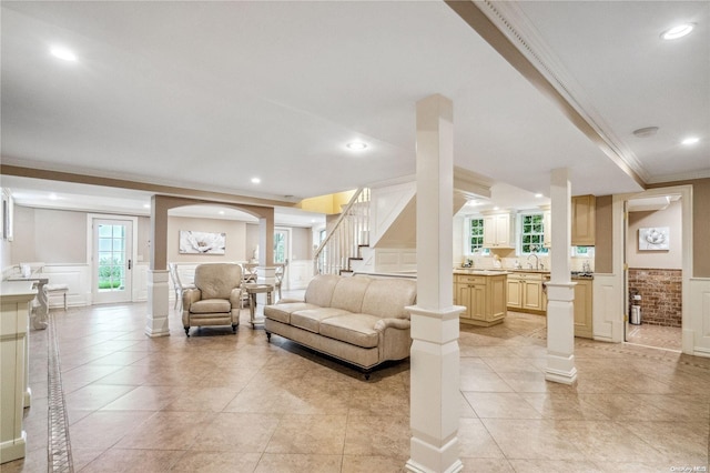 living room with light tile patterned flooring, ornamental molding, and sink