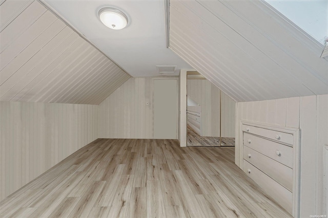 bonus room featuring light hardwood / wood-style flooring, wooden walls, and vaulted ceiling