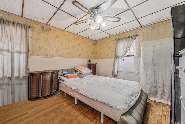 bedroom with a paneled ceiling, ceiling fan, and wood-type flooring