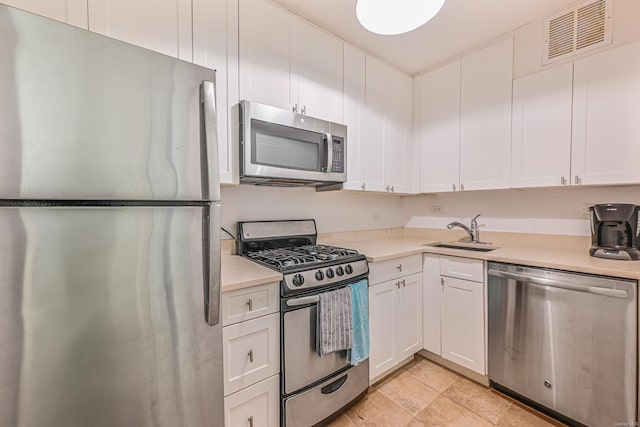 kitchen with stainless steel appliances, white cabinetry, and sink