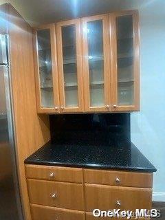 kitchen with stainless steel refrigerator and dark stone counters