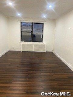 spare room featuring dark hardwood / wood-style flooring and radiator