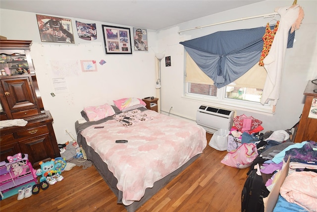 bedroom with a wall unit AC and dark hardwood / wood-style floors