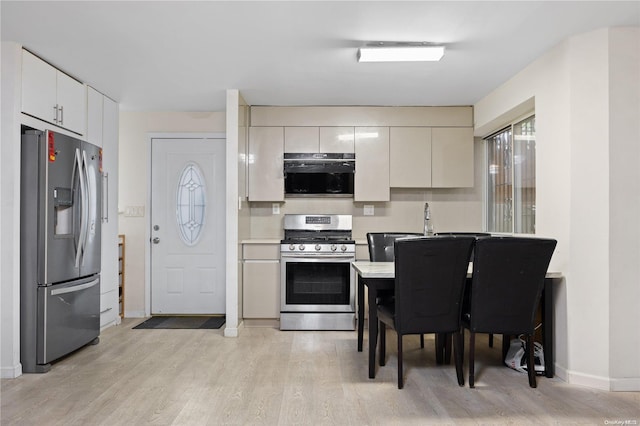 kitchen with white cabinets, light wood-type flooring, and stainless steel appliances