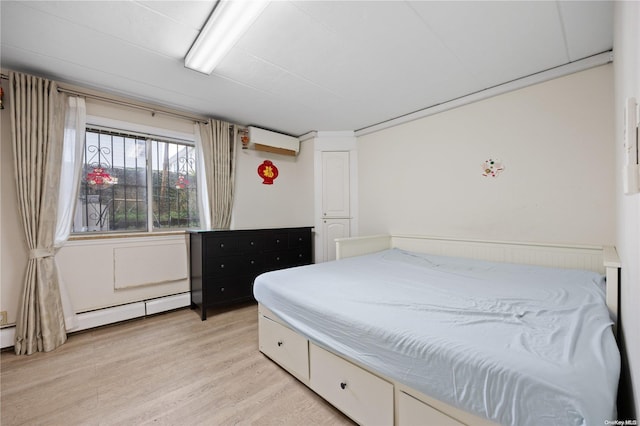 bedroom with a wall mounted AC and light wood-type flooring