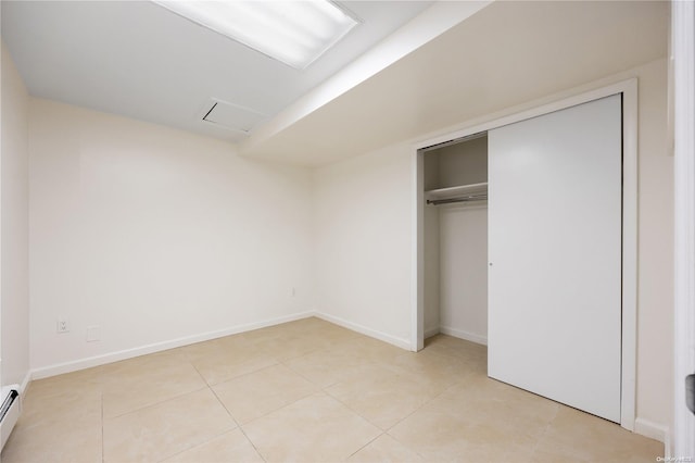 unfurnished bedroom featuring a closet, light tile patterned floors, and a baseboard radiator