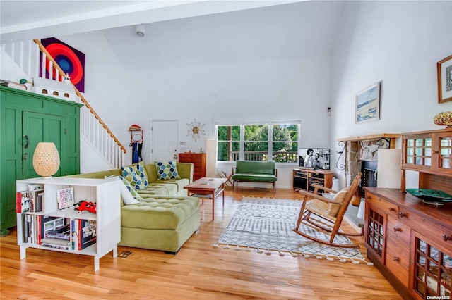 living room featuring a fireplace, a high ceiling, and light hardwood / wood-style flooring