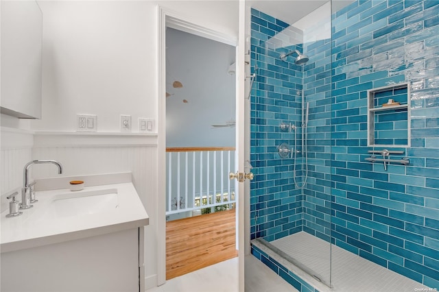 bathroom with hardwood / wood-style floors, vanity, and a tile shower