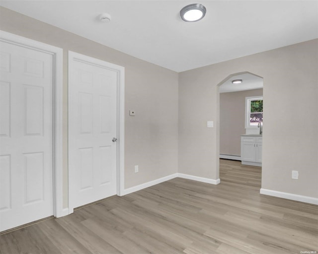 empty room featuring light wood-type flooring and a baseboard radiator