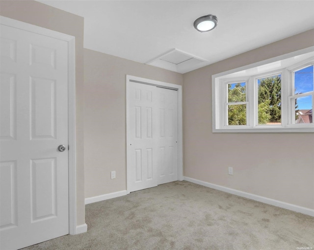 unfurnished bedroom with light colored carpet and a closet