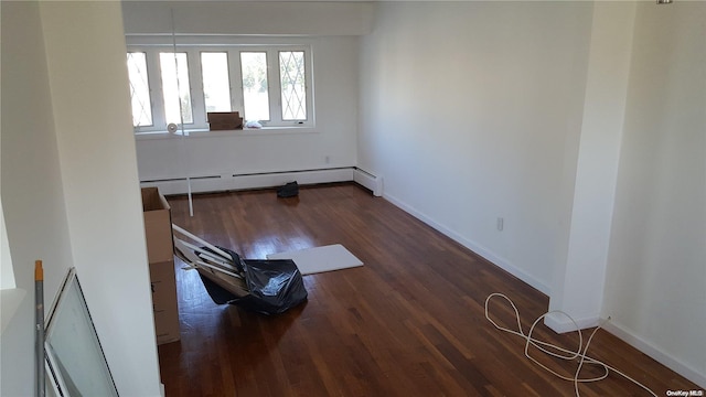 empty room featuring dark hardwood / wood-style floors and a baseboard radiator