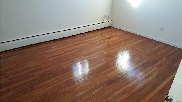 spare room featuring dark hardwood / wood-style floors and a baseboard heating unit