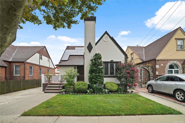 view of front of property with solar panels, a front lawn, and a wooden deck