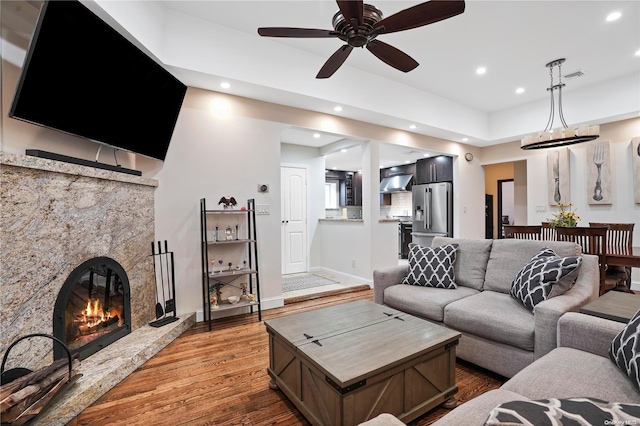 living room featuring hardwood / wood-style floors, ceiling fan, and a high end fireplace