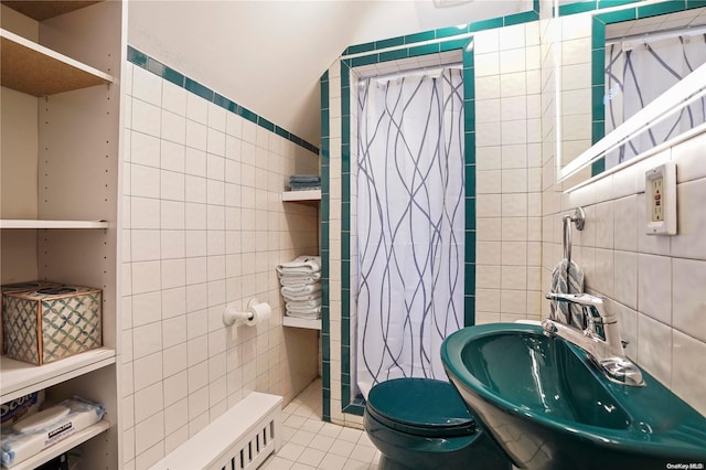 bathroom with sink, tile patterned flooring, lofted ceiling, toilet, and tile walls