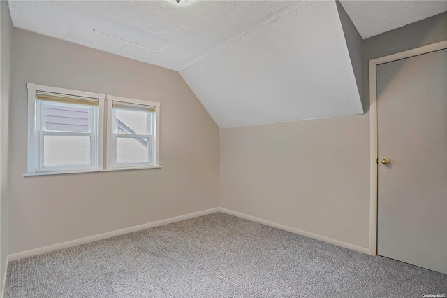 additional living space with carpet, a textured ceiling, and vaulted ceiling