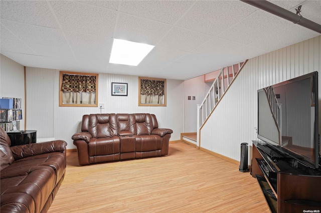 living room featuring wood-type flooring and a paneled ceiling