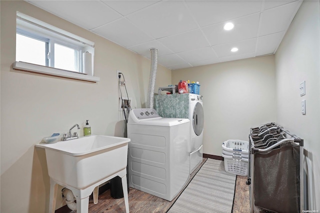 washroom with hardwood / wood-style floors, washing machine and dryer, and sink