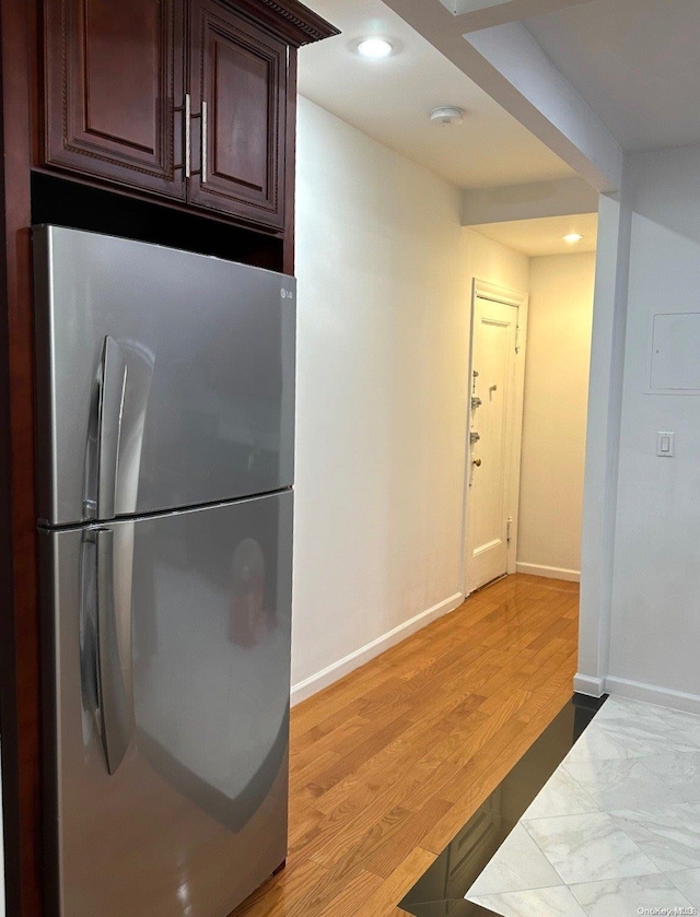 kitchen with stainless steel fridge, light wood-type flooring, and dark brown cabinets