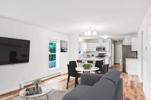 living room featuring a chandelier, light wood-type flooring, a baseboard radiator, and sink