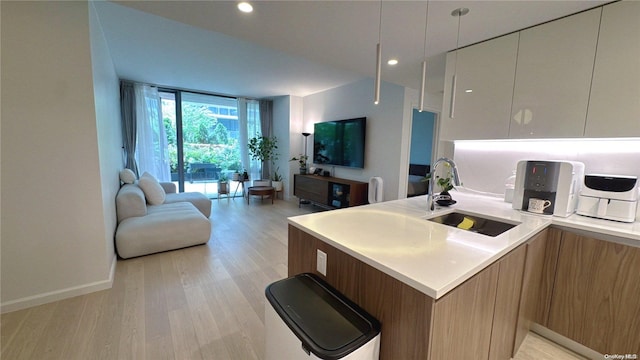 kitchen featuring white cabinets, kitchen peninsula, light wood-type flooring, and sink