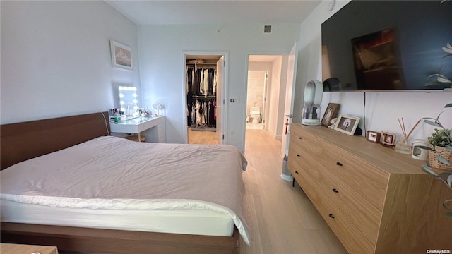 bedroom featuring a walk in closet, a closet, and light wood-type flooring