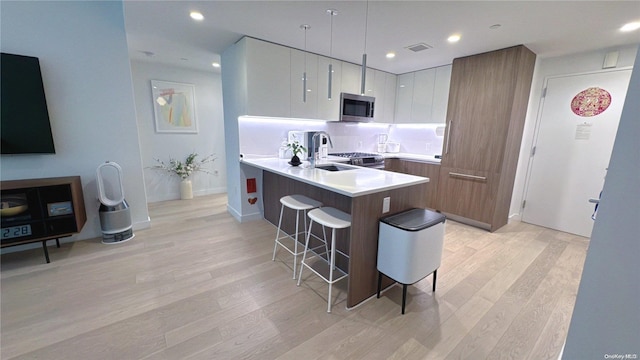 kitchen featuring white cabinets, a kitchen breakfast bar, light wood-type flooring, and backsplash