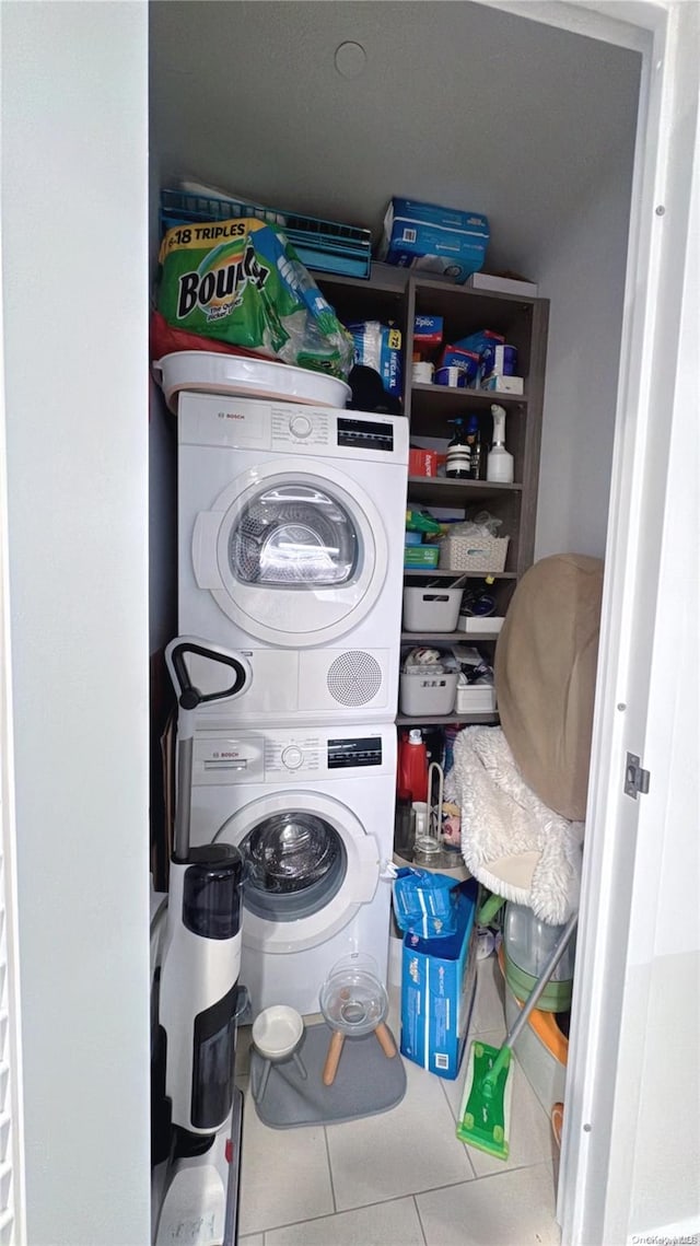 clothes washing area with tile patterned flooring and stacked washer / dryer