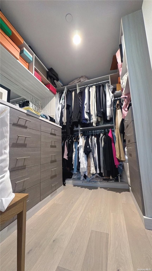 walk in closet with light hardwood / wood-style floors