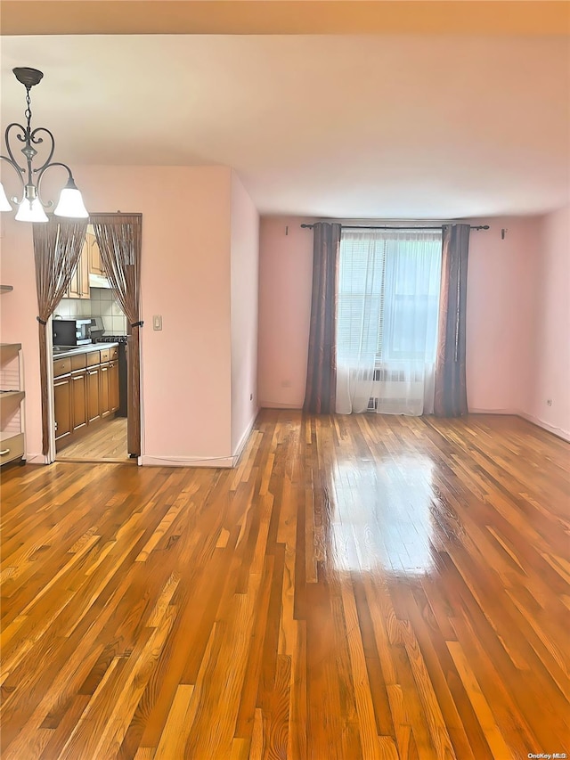 unfurnished living room with a chandelier and hardwood / wood-style floors