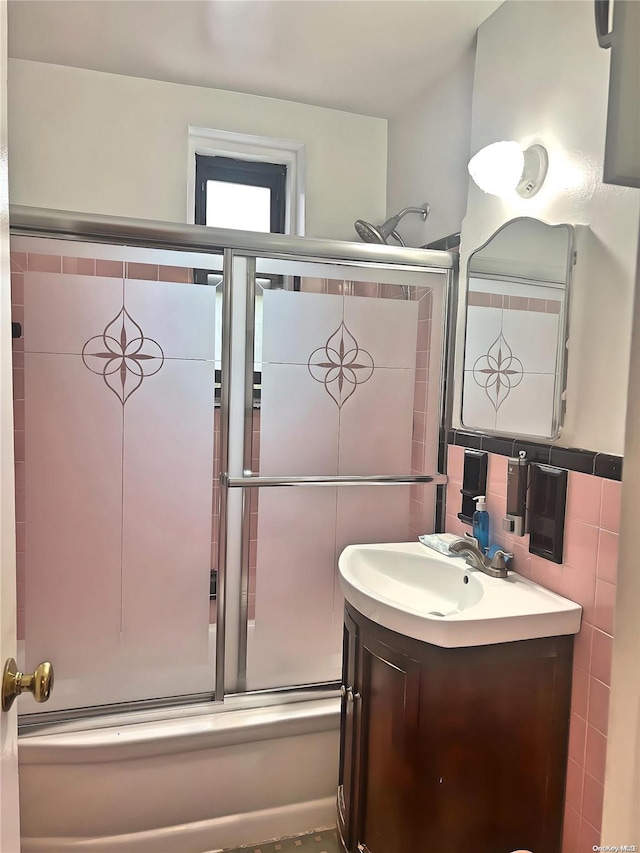 bathroom with tasteful backsplash, vanity, enclosed tub / shower combo, and tile walls