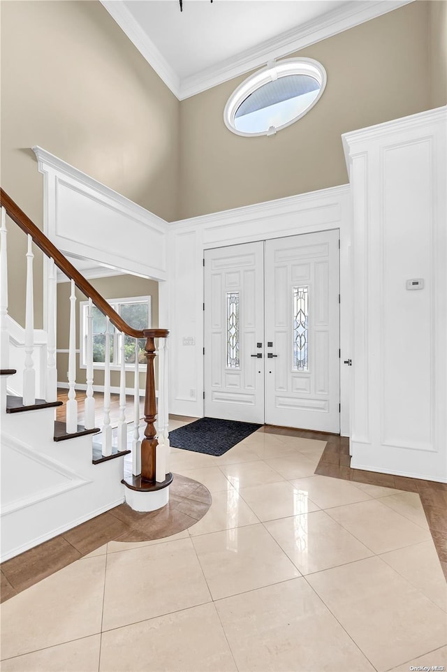 entrance foyer featuring a high ceiling, light tile patterned floors, and ornamental molding