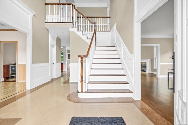 entrance foyer with a high ceiling, wine cooler, light hardwood / wood-style flooring, and crown molding