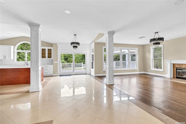 unfurnished living room featuring a high end fireplace, light wood-type flooring, an inviting chandelier, and vaulted ceiling