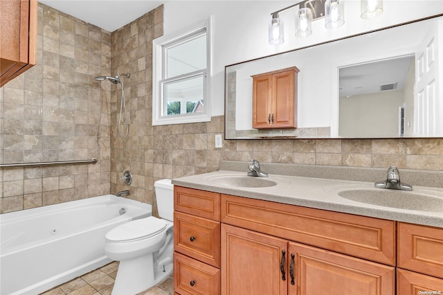 full bathroom featuring vanity, tile patterned flooring, tiled shower / bath combo, toilet, and tasteful backsplash